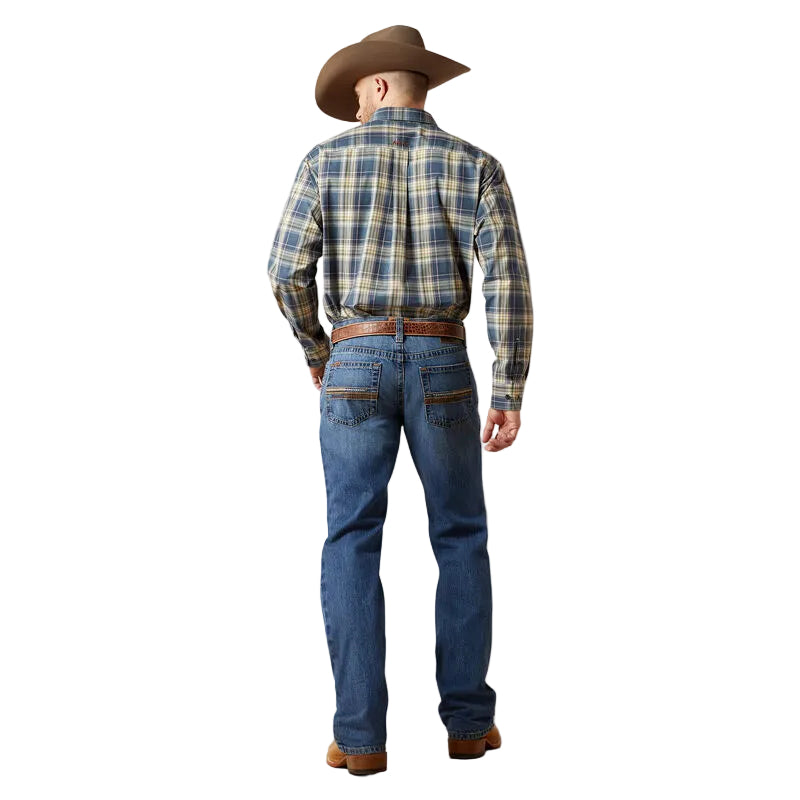 Man wearing a plaid shirt, jeans, and cowboy hat on a plain background
