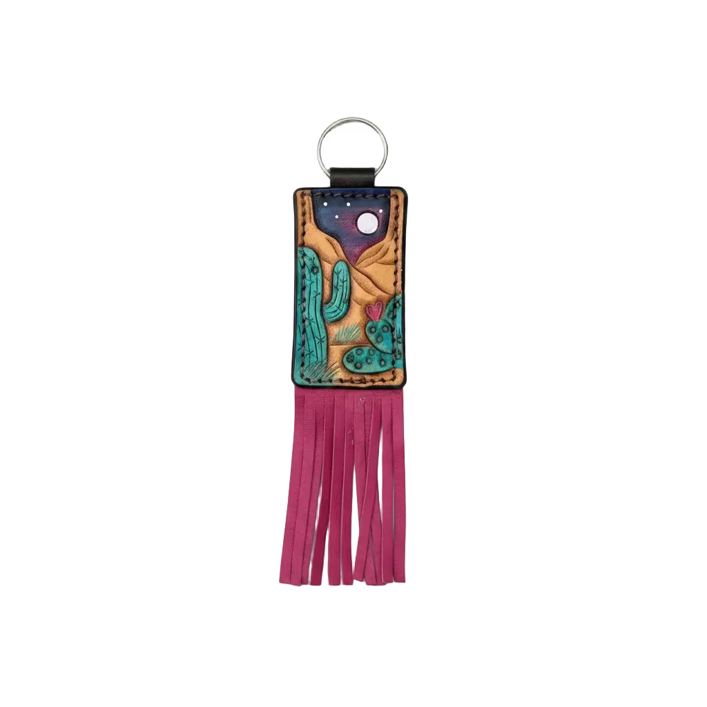 A hand-painted leather keychain wallet featuring a desert cactus design under a starry night sky, with a long magenta fringe tassel and a silver metal key ring, shown against a neutral gray background.