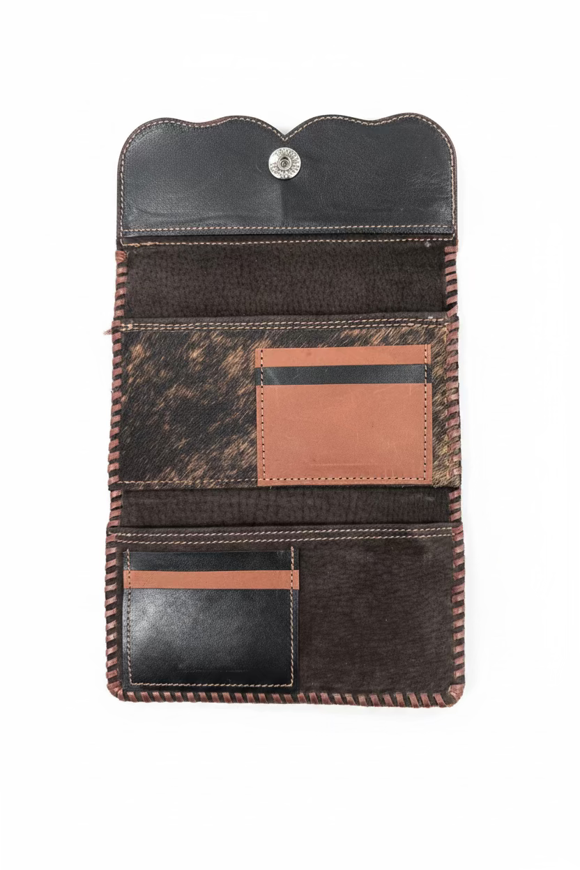 A western-style leather card holder wallet shown open, featuring a black leather top flap with a snap button, a textured brown and black cowhide patterned panel, a tan leather card slot, and a lower black leather card pocket with a tan accent strip.